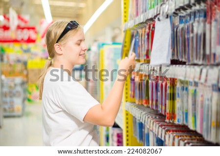 Young woman select writing tools in stationery department in supermarket