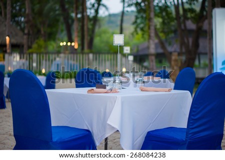 Luxury beach restaurant with tables and chairs covered with white and blue cloth on tropical beach island