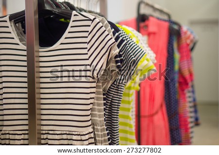Different color and pattern dresses on hangers in clothes store