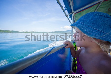 Adorable girl in blue hat on longtail boat in open ocean near islands