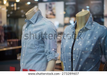 Mannequins in blue jeans shirts with patterns in clothes store