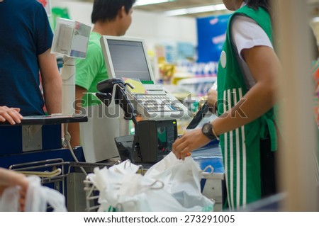 Cash desk with cashier serving customers in supermarket