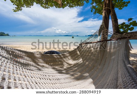 Huge empty hammock under palm tree at the ocean beach in sunny day