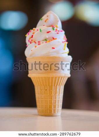 Ice cream cone with rainbow color sprinkles on blurry background