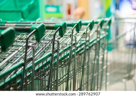 Row of green shopping carts in front of entrance to supermarket
