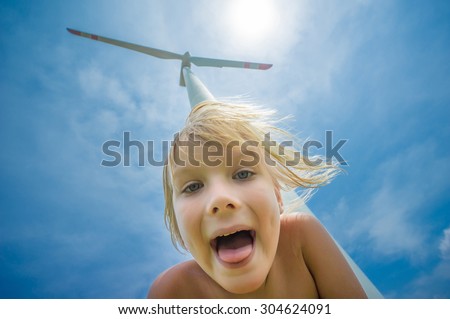Adorable girl in front of giant  white wind turbine generating electricity on blue sky
