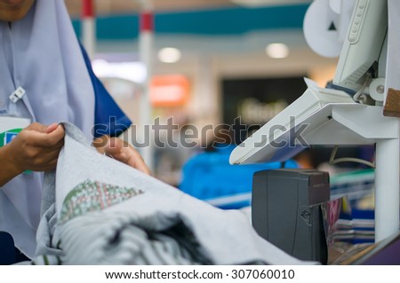Cashier serves customer at cash desk with computer terminal in supermarket