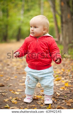 young adorable baby walk by road in leaves  in park forest