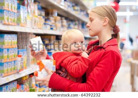 Young mother with baby daughter shopping in supermarket