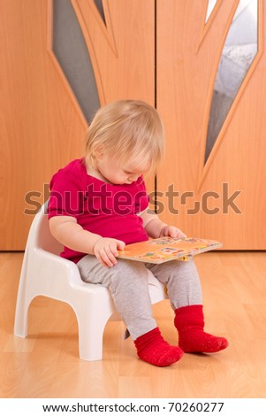 Adorable baby sit on floor and read small baby book