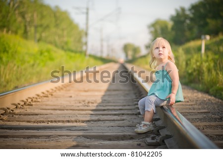 Adorable toddler girl sit on rail wait for train