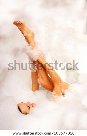 Young woman enjoys bath-foam in the bathtub.