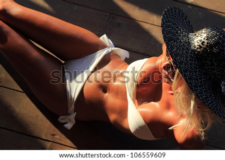 Sexi fit bikini model with hat posing on wooden floor - shallow DOF