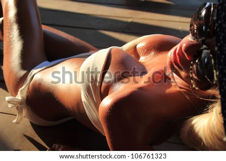 Sexi fit bikini model with hat posing on wooden floor - shallow DOF