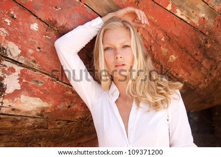 portrait of sexy blond woman posing in from of shipwreck