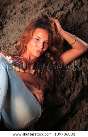 Beautiful young sexy fashion model in jeans by the sea at sunrise