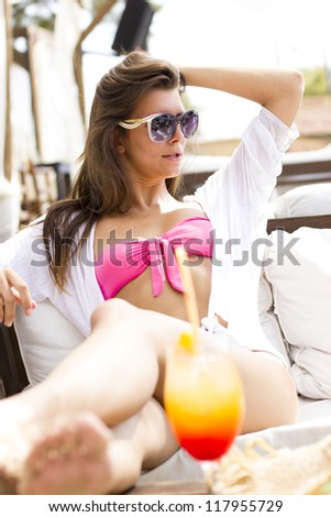 Young woman relaxing at summer lounge bar enjoying a fresh cocktail