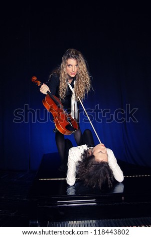 Two beautiful young sexy women posing with violon and piano