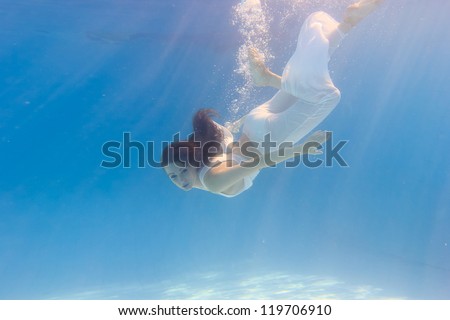 Woman wearing a white dress underwater in swimming pool