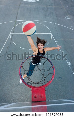 Young basketball player on the street going to the hoop. Great angle from above. Focused on the basket