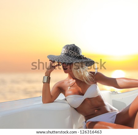 Young sexy woman in white bikini enjoying the sunset on her private yacht