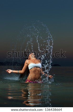 Beautiful young woman in bikini in the sea splashing water