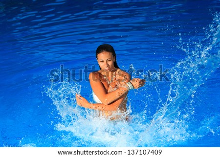 Young beautiful woman splashing water in swimming pool