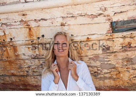portrait of sexy blonde woman posing in from of shipwreck