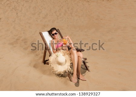 Beautiful young woman in bikini on the beach enjoying a fresh cocktail
