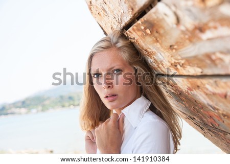 portrait of sexy blond woman posing in from of shipwreck