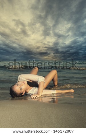 Beautiful young woman in bikini laying on the beach