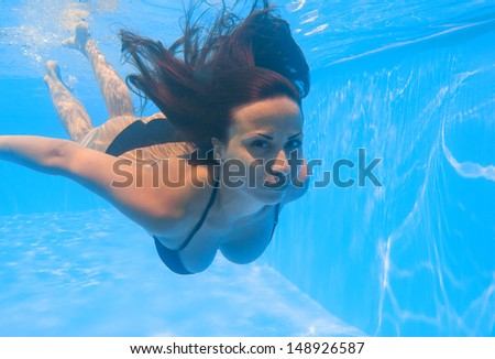Young woman swimming underwater in the swimming pool