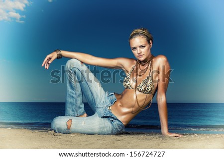 Beautiful young sexy fashion model in jeans by the sea in Greece
