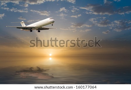 commercial jet airplane in flight at sunset above the sea