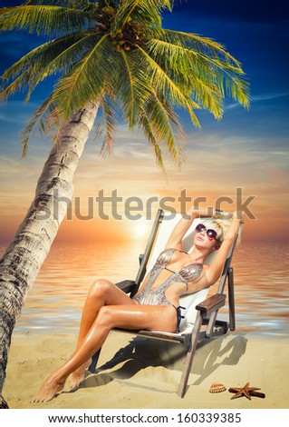 Beautiful young woman in bikini on the beach onder a coconut tree