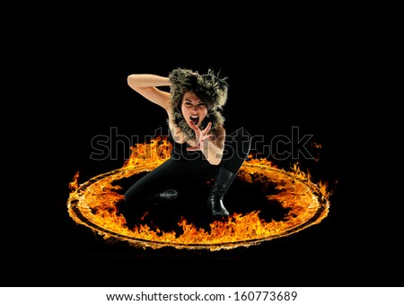 Woman in a circle of fire Blazing flames over black background