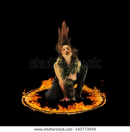 Woman in a circle of fire Blazing flames over black background