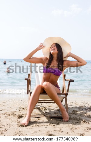 Beautiful young woman in bikini sitting on the beach