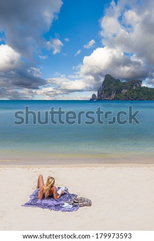 Young blonde woman reading a book on Phi Phi island beach in Thailand