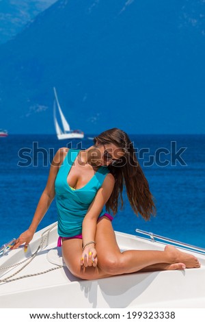 Young sexy woman on her private yacht with sailing yachts on background