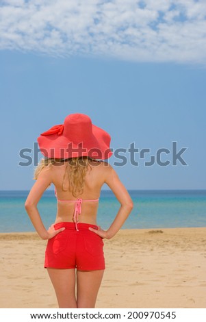 Young woman on tropical beach in red shorts