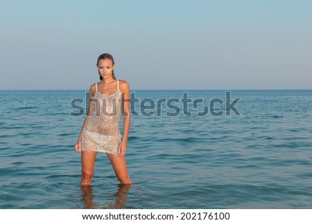 young sexy girl in bikini and wet shirt at the beach. Sensual attractive woman in water wearing bikini. Woman with perfect body relaxing on the beach.
