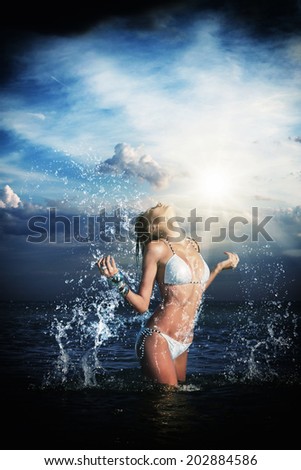Beautiful woman jumps out of the sea leaving a big splash