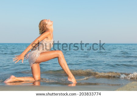 young sexy girl in bikini and wet shirt at the beach. Sensual attractive woman in water wearing bikini. Woman with perfect body relaxing on the beach.