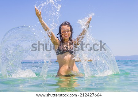 Beautiful young woman in the sea splashing water