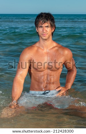 Portrait of a handsome young muscular man in swimwear on the beach