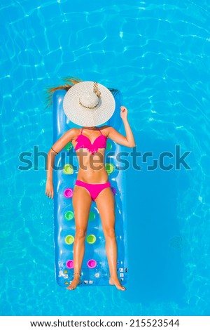Top view of a  girl in the swimming pool relaxing on a lilo