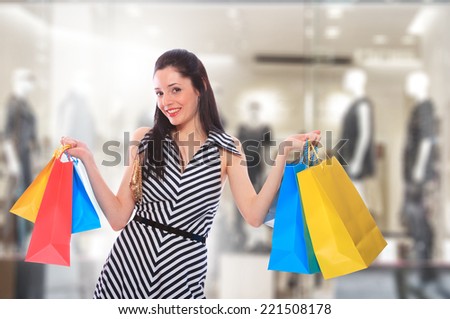 young woman holding shopping bags in front of the store