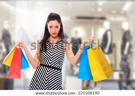 young woman holding shopping bags in front of the store