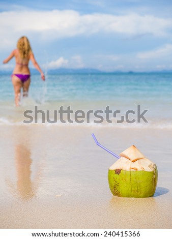 Woman on the tropical beach with young coconut fresh drink selective focus